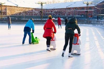 Winter rink. girls on skates ride on ice. active family sport during kids