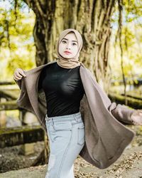 Portrait of woman standing on tree trunk