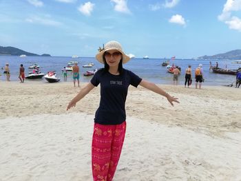 Portrait of woman with arms outstretched standing at beach