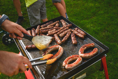 High angle view of men preparing sausages on barbecue grill in yard