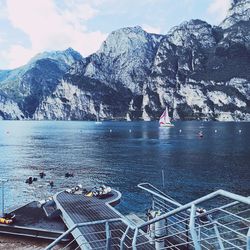 High angle view of sea by snowcapped mountains against sky