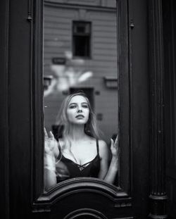 Portrait of young woman standing against door of building