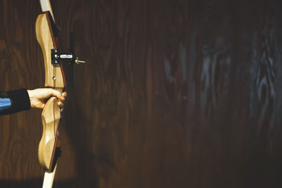 Close-up of person holding bicycle against wall