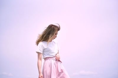 Low angle view of woman standing against pink sky