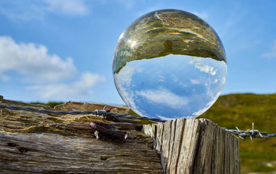 Crystal ball on a weathered wooden fence post with barbed wire, dune landscape with beach grass