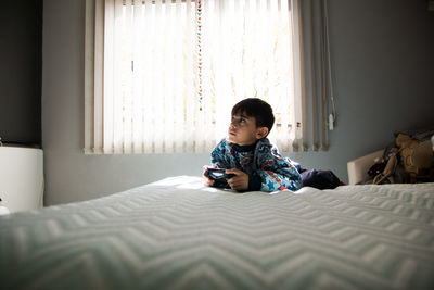 Boy sitting on bed at home