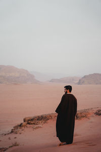 Rear view of woman standing at desert