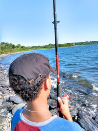 Rear view of man by sea against clear sky