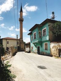 Street leading towards buildings against sky