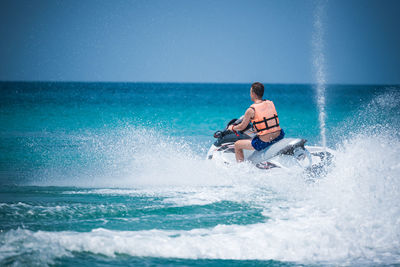 Man surfing on sea against clear sky