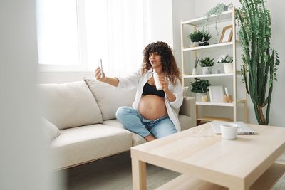 Young woman using digital tablet while sitting on sofa at home