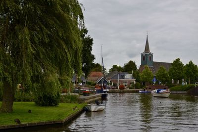 Boats moored in river against cloudy sky