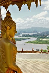 Statue of buddha and buildings against sky