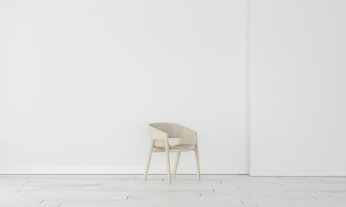 Empty chair against white wall