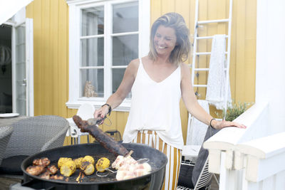 Smiling woman preparing food on barbecue