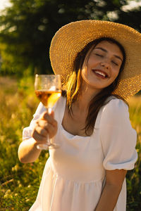 Young beautiful girl in a white dress having a picnic with a glass of champagne or white wine