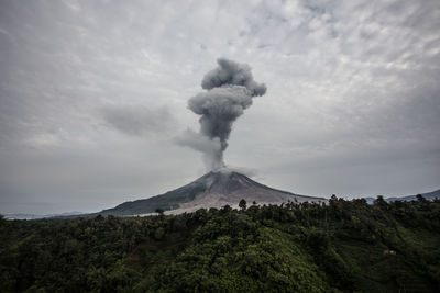 Scenic view of smoke emitting from volcanic crater against sky