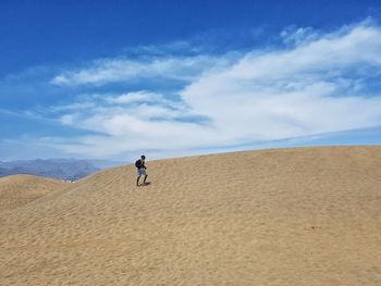 Man riding motorcycle on sand at beach against sky