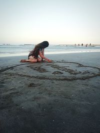 Woman on beach against clear sky