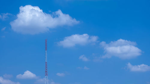 The signal towers have a sky and clouds in the background