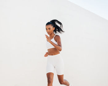 Portrait of young woman standing against wall