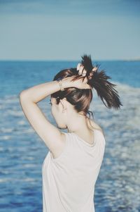 Woman standing by sea against sky