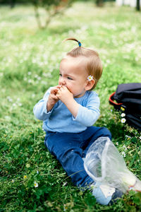 Cute girl looking away while sitting on grass