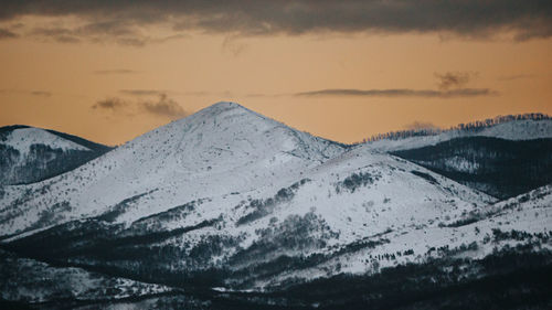 Scenic view of snowcapped mountains against sky during sunset