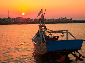 Ship moored in sea against sky during sunset