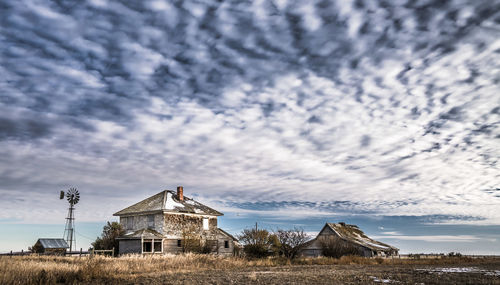 Abandoned house on field against sky