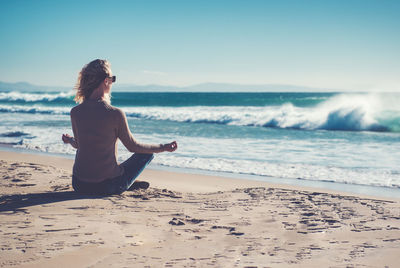 Young woman on beach against clear sky