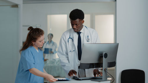 Nurse showing file folder to doctor at desk in hospital