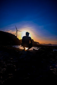 Rear view of silhouette man standing on beach during sunset