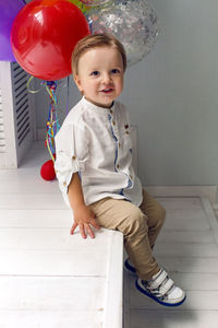 Portrait of a child boy two years old sitting on a wooden floor with balls and number two