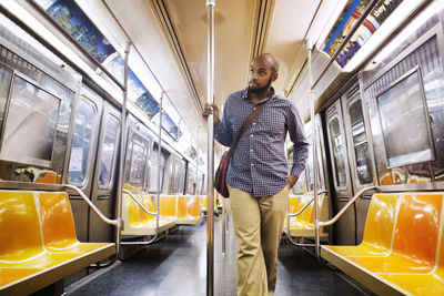 Man with hand in pocket looking away while traveling in train