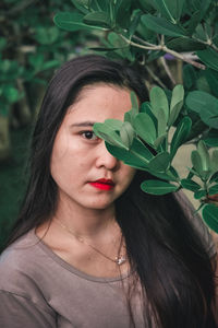 Close-up portrait of young woman with leaves