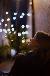 Side view of woman looking at illuminated  decorations for christmas 