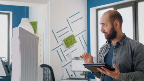 Portrait of young man using mobile phone in office