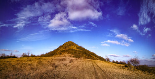 Scenic view of arid landscape against blue sky