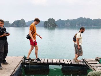 Friends standing on lake against sky