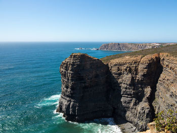 Rock formation in sea against clear sky