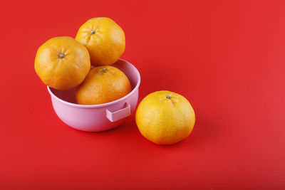 Close-up of fruits in bowl against orange background