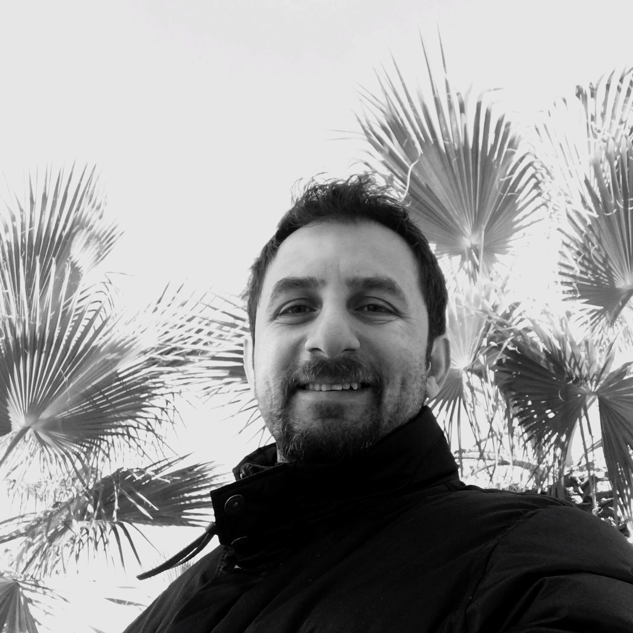 portrait, beard, real people, headshot, one person, looking at camera, front view, lifestyles, outdoors, tree, low angle view, young adult, palm tree, clear sky, growth, day, men, nature, close-up, sky, smiling