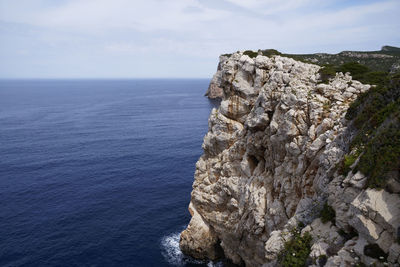 Rock formation by sea against sky