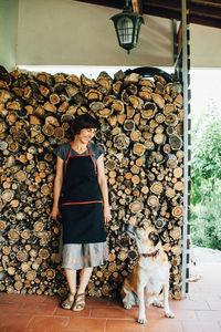 Professional female woodworker and dog at the pile of logs