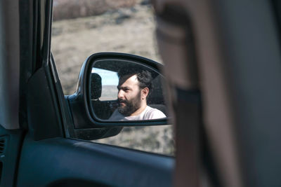 Reflection of man on side-view mirror