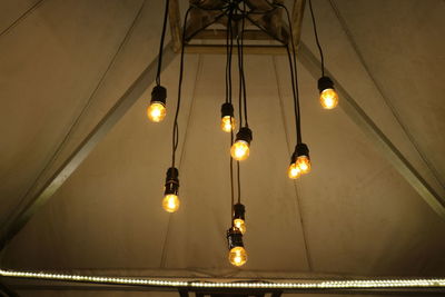 Low angle view of illuminated light bulbs hanging from ceiling