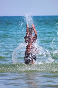 Teenage boy splashing water in sea