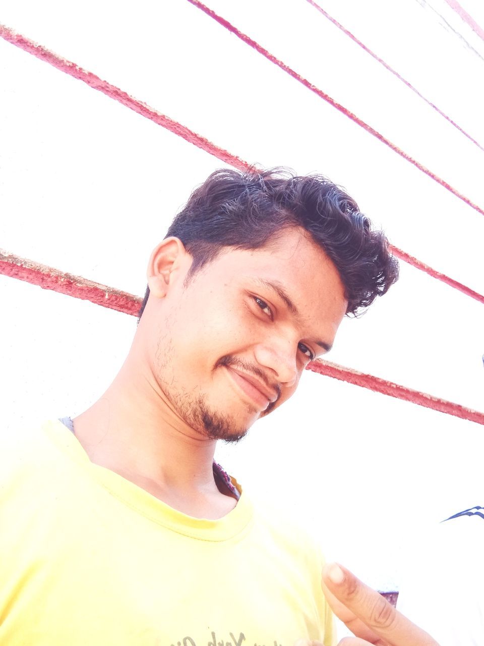 PORTRAIT OF SMILING YOUNG MAN AGAINST WALL