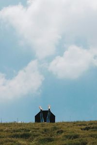 Woman falling with umbrella on grassy field against cloudy sky